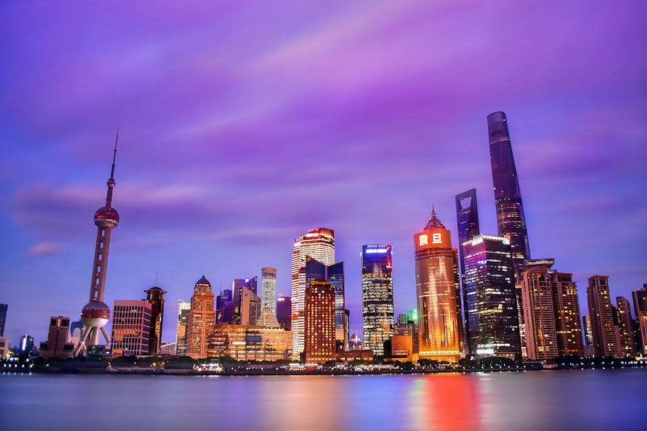 A vibrant skyline of Shanghai's modern skyscrapers reflected in the water during dusk.